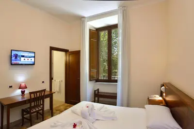 a bedroom with a bed and a desk and a window at Casa I Cappuccini in Rome