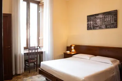 a bedroom with a bed and a desk and a window at Casa I Cappuccini in Rome
