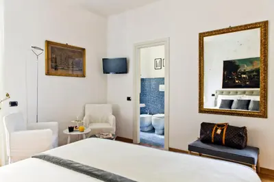 a bedroom with a bed and a mirror and a chair at Garibaldi Suites Piazza Di Spagna in Rome