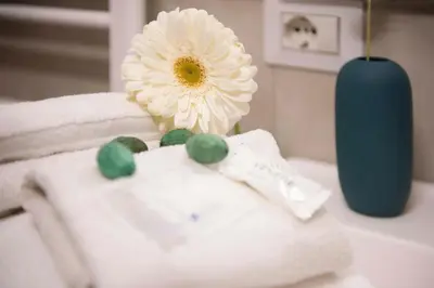 a white flower sitting on top of a pile of towels at Stranamore Apartments Trastevere in Rome