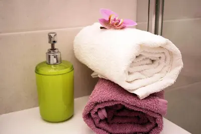 a green bottle of soap and towels on a bathroom sink at Bye Bye Roma Pantheon Suite in Rome
