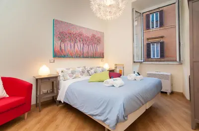 a bedroom with a bed with a red chair and a painting at Bye Bye Roma Pantheon Suite in Rome