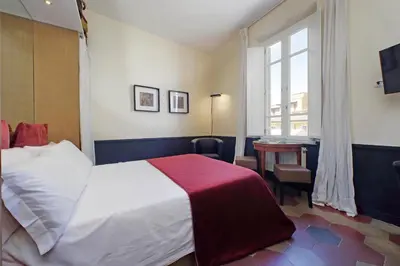 a bedroom with a bed and a desk and a window at Michelangelo Charmsuite in Rome