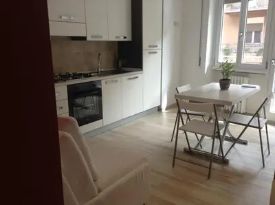 a kitchen with white cabinets and a table and chairs at Your Rhome in Rome
