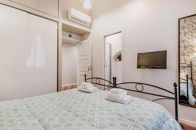 a white bedroom with a large bed and a tv at B&B Trastevere 94 in Rome