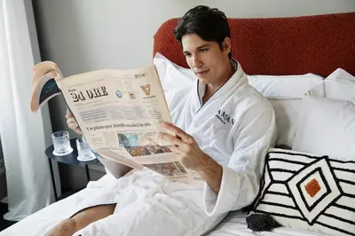 a man sitting in bed reading a newspaper at HOTEL VITE - By Naman Hotellerie in Rome
