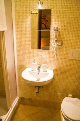 a bathroom with a sink and a toilet and a mirror at Mosaic Central Guest House in Rome