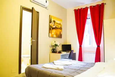 a bedroom with a bed and a window with red curtains at Mosaic Central Guest House in Rome