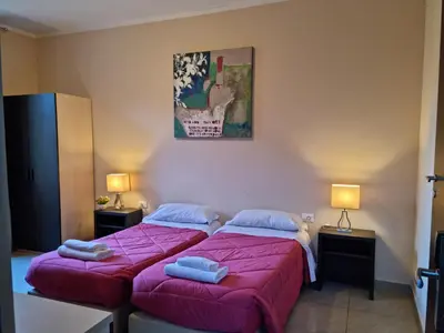 two beds in a small room with two lamps at Hostel Mosaic in Rome