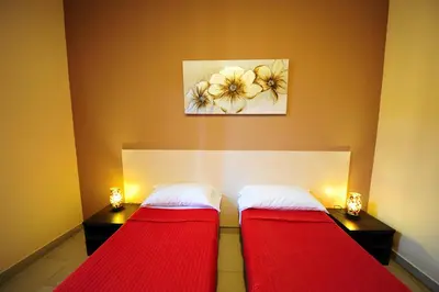 two beds in a room with red sheets and a painting at Hotel Mosaic Central Rome in Rome