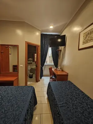 a hotel room with a bed and a desk and a room at Domus Roxy in Rome