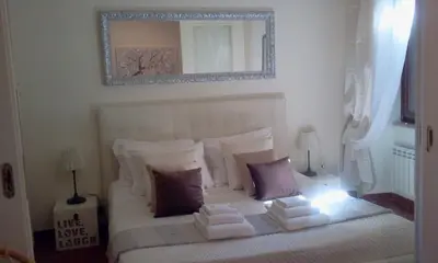 a bedroom with a white bed with pillows and a mirror at Casina Tiberina in Rome