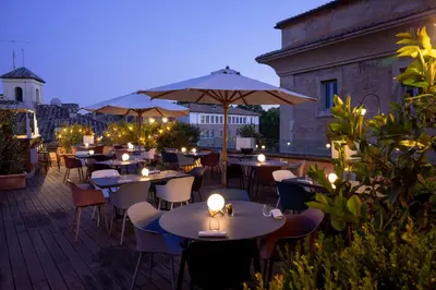 a row of tables and chairs with candles on a patio at DOM Hotel Roma - Preferred Hotels & Resorts in Rome