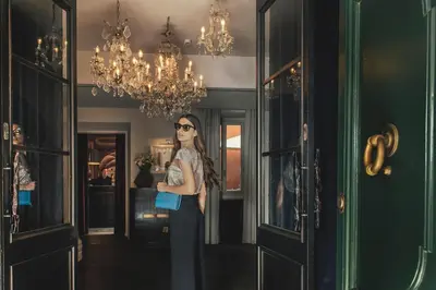 a woman standing in a hallway with a blue purse at DOM Hotel Roma - Preferred Hotels & Resorts in Rome