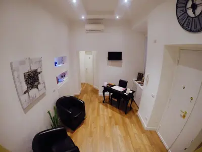 a living room with a desk and a clock on the wall at Tre R Colosseo in Rome