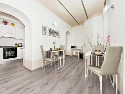 a white kitchen and dining room with a table and chairs at White Rooms Colosseo in Rome