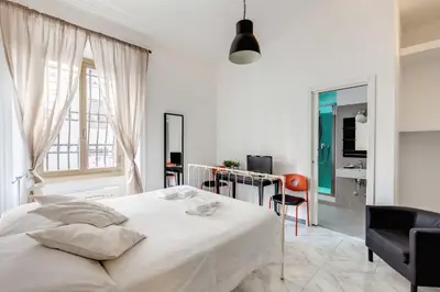 a white bedroom with a bed and a desk at Locanderia Roma in Rome