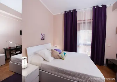 a bedroom with a white bed with purple curtains at B&B St. Peter's Suites in Rome