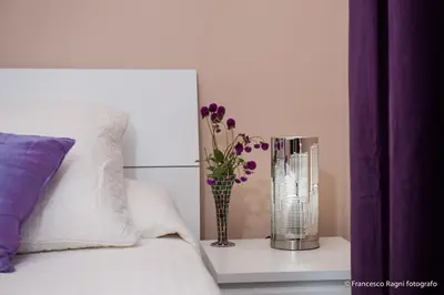 a vase with purple flowers on a table next to a bed at B&B St. Peter's Suites in Rome
