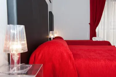 a red bed with a red blanket and a table with a lamp at Domus Fabiola - Vaticano in Rome