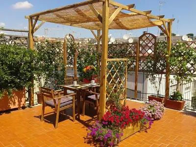 a patio with a table and chairs and flowers at Holiday rental St Peter's area in Rome