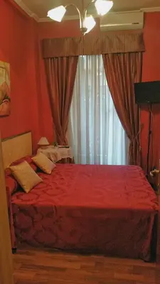 a bedroom with a bed with red sheets and a window at Petite Maison in Rome