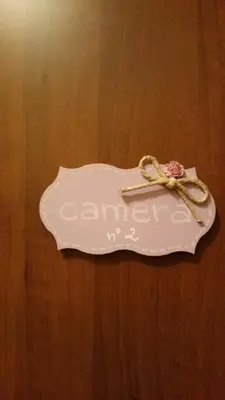 a white tag with a pink flower on a wooden table at Petite Maison in Rome