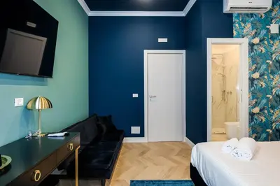 a bedroom with blue walls and a bed and a couch at Suri Suites in Rome
