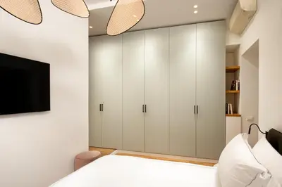 a bedroom with white cabinets and a flat screen tv at Casavignoni elegant 3BR home near to Spanish step in Rome