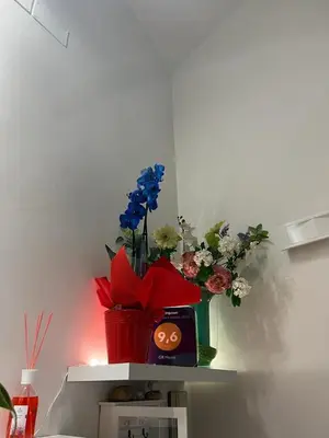 a shelf with a vase of flowers and a clock at Marcelina vaticans rooms in Rome