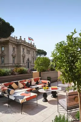 a patio with couches and tables in front of a building at W Rome in Rome