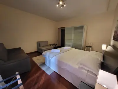 a bedroom with a large white bed and a chair at Colosseo Homerents 2 in Rome