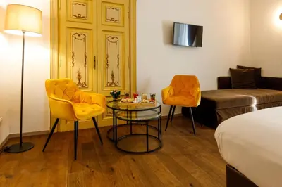 a hotel room with a bed and two chairs and a table at V Collection Piazza Farnese Luxury Suites in Rome