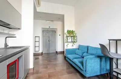 a living room with a blue couch and a kitchen at SuitInn19 in Rome