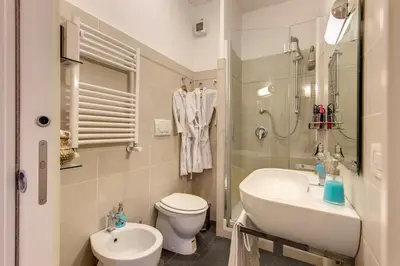 a white bathroom with a sink and a toilet at Elegant Apartment Behind the Colosseum in Rome