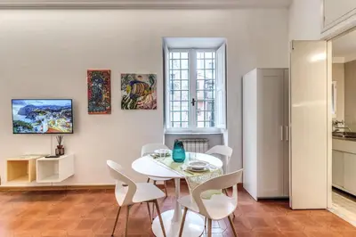 a white dining room with a white table and chairs at Elegant Apartment Behind the Colosseum in Rome