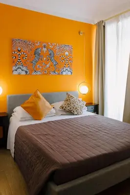 a bedroom with a bed with an orange wall at The B Place Cola in Rome