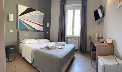 a hotel room with a bed and a desk and a window at Napoleone Suite in Rome