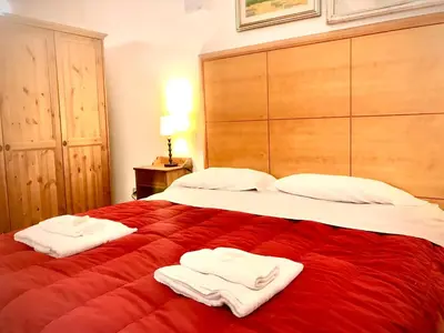 a bedroom with a large red bed with towels on it at Le Sibille in Rome