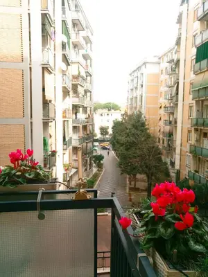 a balcony with red flowers on a city street at Green Line in Rome