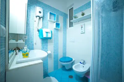 a blue tiled bathroom with a toilet and a sink at Green Line in Rome