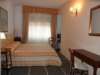 a hotel room with a bed and a desk and a window at B&B Le Sibille in Rome