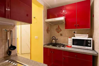 a small kitchen with red cabinets and a microwave at Domus Clodio in Rome