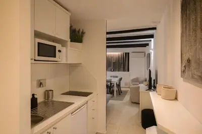 a kitchen with white cabinets and a living room at Trust-Trastevere in Rome