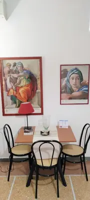 a table with two chairs and two paintings on the wall at Trionfal Apartment in Rome