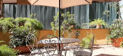 a table and chairs with an umbrella in a garden at Trionfal Apartment in Rome