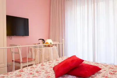 a bedroom with pink walls and a bed with a red pillow at Malkavacanze B&B in Rome