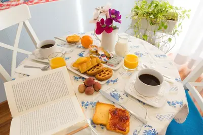 a table with breakfast foods and coffee and a book at Malkavacanze B&B in Rome