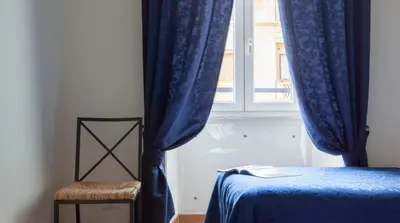 a bedroom with blue curtains and a bed and a window at Otium Maecenatis Apartments in Rome