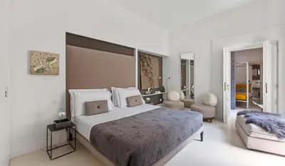 a white bedroom with a large bed and a chair at Piazza di Spagna 9 in Rome